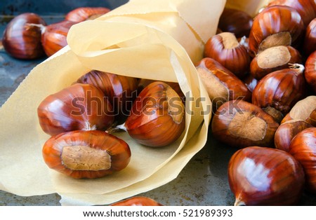 Tasty ripe chestnuts in a pepper cone on vintage metal background.