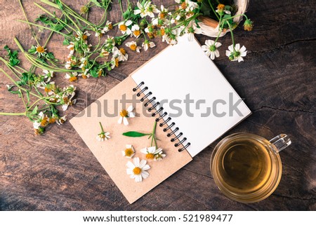 Blank notebook white flower and bas ket of flower and cup of tea on vintage wooden table View from above with copy space