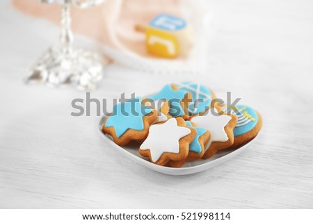 Plate with tasty glazed cookies for Hanukkah on light wooden table