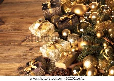 Christmas theme, christmas decoration. presents in boxes on a wooden table with golden baubles, clove, cardamon, star anise, cinnamon. Golden and brownish aesthetics. Place for typography and logo.