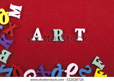 Art multicolour word composed from wooden alphabet letters on red background.