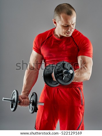 Athletic man doing biceps curl with dumbbells, studio shot