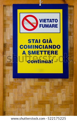 "Vietato Fumare" ("No Smoking") signboard in italian language with the message "Se stai cominciando a smettere continua" ("if you're trying to stop go on"), hanging from a wooden screen