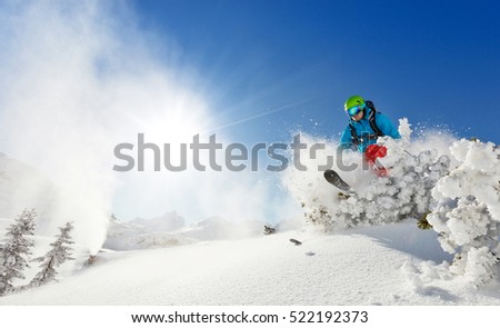 Freeride skier with rucksack running downhill in freeze motion of snow powder. Royalty-Free Stock Photo #522192373