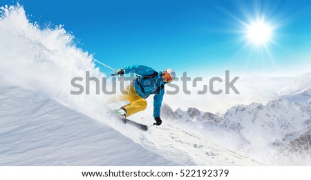 Skier on piste running downhill in beautiful Alpine landscape. Blue sky on background. Free space for text Royalty-Free Stock Photo #522192379
