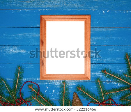Empty wooden photo frame on a blue festive wooden background with branch fir