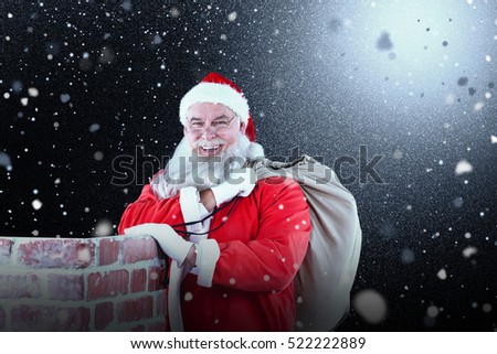 Portrait of Santa Claus with eyeglasses carrying bag full of gifts against snow with red flakes