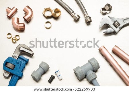 Various plumbers tools and plumbing materials including copper pipe, elbow joint, wrench and spanner. shot on a bright stainless steel background. Royalty-Free Stock Photo #522259933