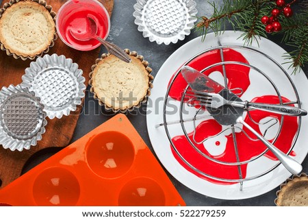 Cooking modern dessert for winter holiday party - festive tartlet cake with souffle or mousse and red mirror glaze shaped santa claus hat