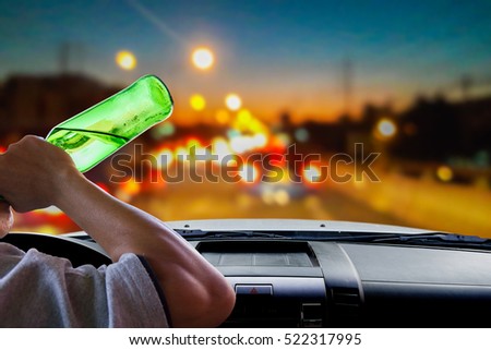 Man drinking beer while driving, beautiful bokeh on the road at twilight as background.