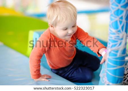 Active toddler boy playing at indoors playground or leisure center