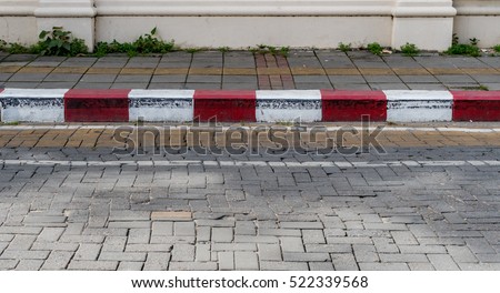 Concrete sidewalk with red and white curb