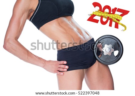 Female bodybuilder holding large black dumbbell mid section against digitally generated image of 3D new year with tape measure