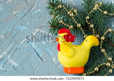 Festive Christmas background with fir branches, beads, cock on the textured surface of the blue and gray putty. Rooster - symbol of the new year 2017 on the eastern calendar free space for text