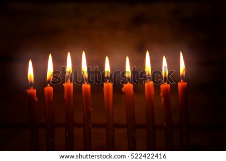 Nine burning candles on dark blurred background, closeup. Hanukkah concept