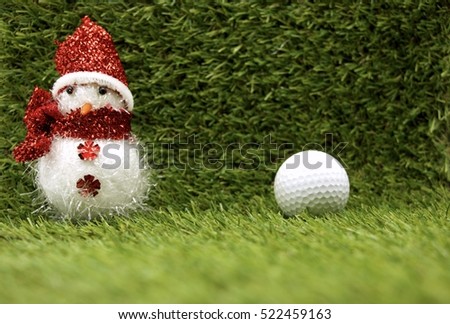 Snowman with golf ball and Christmas gift box on green grass background