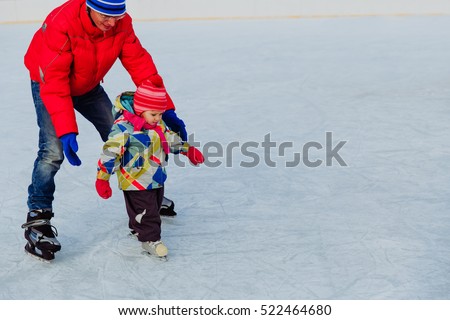 father teaching little daughter to skate in winter
