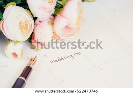 word wedding on calendar with sweet flowers and pen  ,love concept Royalty-Free Stock Photo #522470746