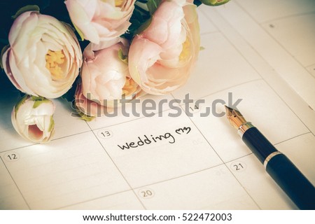 word wedding on calendar with sweet flowers and pen  ,love concept Royalty-Free Stock Photo #522472003