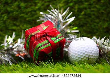 Golf ball and Christmas gift box on green grass background