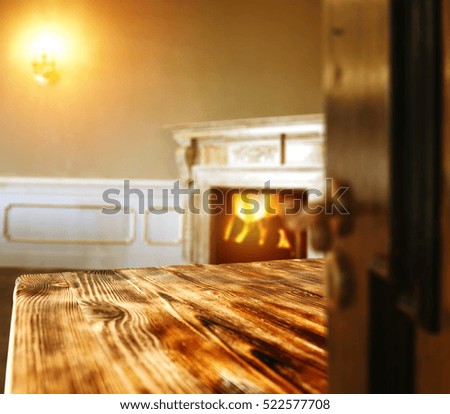 Wooden table of free space for your decoration and interior with fireplace and blurred old brown door 