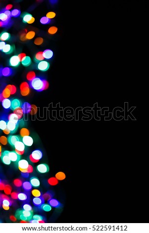 Color light blurred border on black background, unfocused. Christmas or other holiday decorations, garland illumination bokeh. Colorful abstract spots