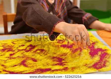 child's hands drawing with glitter