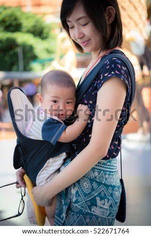 Portrait of a happy mother holding baby in Baby Carriers