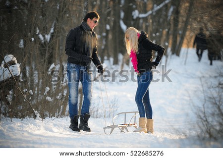 young cheerful man and woman on a sled and enjoy the winter riding
