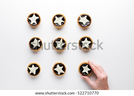The hand puts star shaped tarts on the table, top view, on white