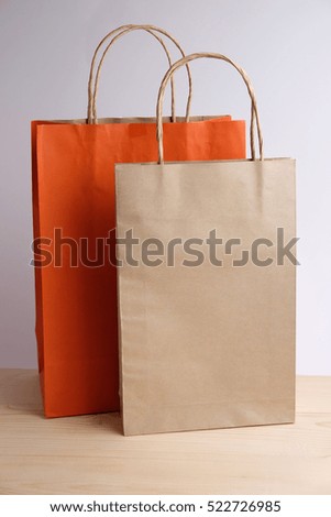 Orange and brown paper bag isolated with shopping concept on wooden and gray background. Blank space and close up.