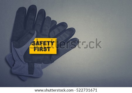 Safety first card in protective gloves on dark background
