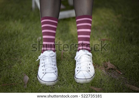Closeup of legs wearing striped socks and white sneakers
