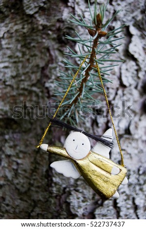 Funny natural, golden angel figurine in exterior, tree trunk, silver fire branches, space for text