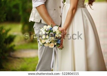 Wedding bouquet in hands of bride and groom in wedding day Royalty-Free Stock Photo #522806515