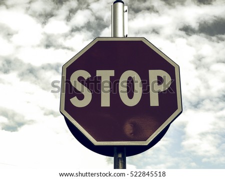 Vintage looking Stop traffic sign over blue sky with clouds