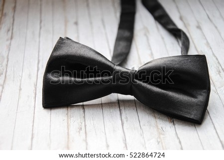 Men's black bow tie on a wooden background. Accessory for formal dress. Symbol of elegance and fashion for men. Men's casual. Royalty-Free Stock Photo #522864724