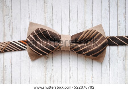 Brown stripes bow tie on a wooden background. Men's and women's accessories. Hipster style. Royalty-Free Stock Photo #522878782