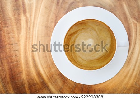Top view of hot coffee cappuccino latte cup with saucer on wood texture abstract background.