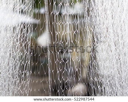 Abstract white textile blurry background. Water like abstraction in blur. Polyester net closeup photo for backdrop. Thin thread blurry background. Fisherman net close-up image. Plastic curtain picture