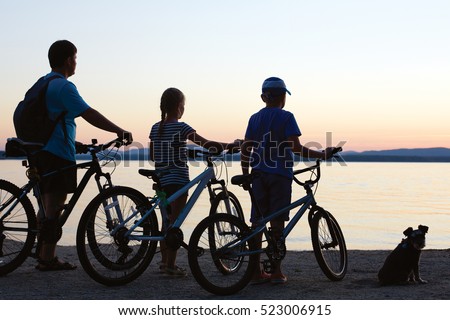 Biker family silhouette. Happy family - father with two kids on bikes with dog