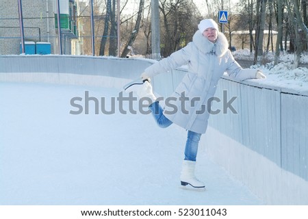 Girl in winter clothes skate on fenced rink, Moscow region