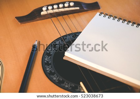 Music concept, Notebook and pencil on guitar for writing music