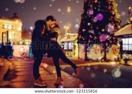 Christmas market. Christmas tree. Kissing couple. Blurred background suitable to be used to promote anything about christmas. 