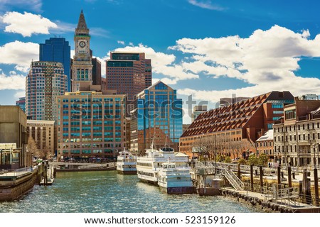 Ships and boats moored at the pier near the center of Boston in the United States. The city is surrounded by water and people often use water transport to avoid traffic jams in on the streets.