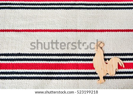 Wooden rooster on a carpet  background.
 Nice natural holiday greeting card template. Empty space for text, copy, lettering.
