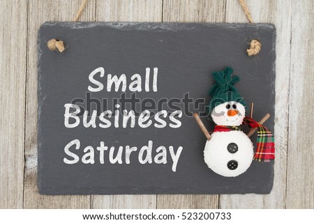 Old fashion Christmas store message, A retro chalkboard with a snowman hanging on weathered wood background with text Small Business Saturday