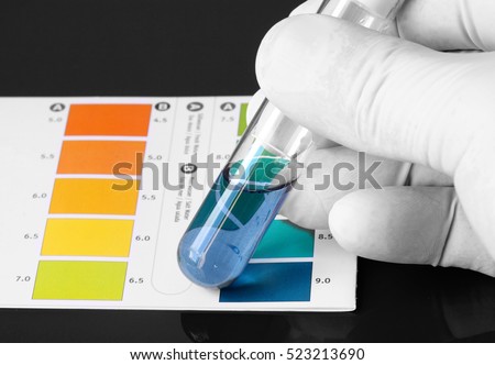 Person wearing gloves testing the PH of a chemical in a test tube Royalty-Free Stock Photo #523213690