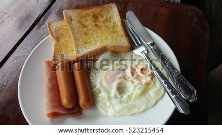 breakfast with fried eggs, toasts, sausage, hotdog and ham.