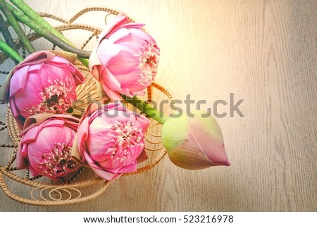 Blurry a bouquet of lilies in a basket and artificial light and copy space. Lotus flower on wooden background.